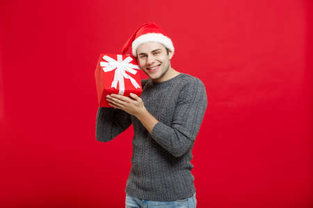 Christmas Concept - handsome young man in sweater with red christmas giftの写真素材