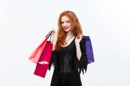 Halloween witch concept - Happy Halloween Witch smiling and holding colorful shopping bags on white background.の写真素材