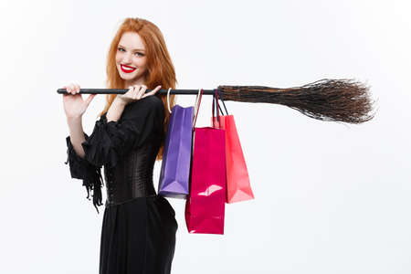 Halloween witch concept - Happy Halloween Witch smiling and holding colorful shopping bags on white background.の写真素材