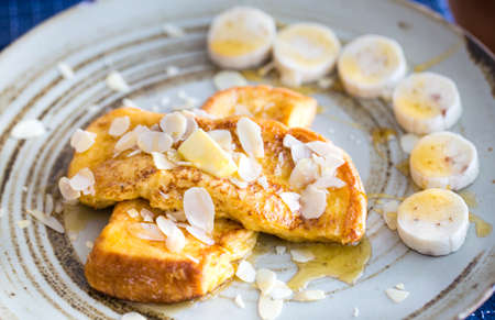 Plate of delicious French toast with bananas and maple syrup on topの写真素材