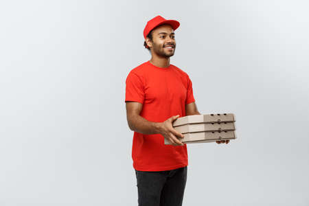 Delivery Concept - Portrait of Handsome African American Pizza delivery man. Isolated on Grey studio Background. Copy Space.の写真素材