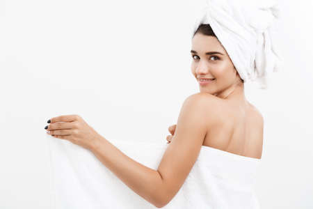 Beauty and Skin care concept - Beautiful caucasian Young Woman with bath towel on head covering her breasts, on whiteの写真素材