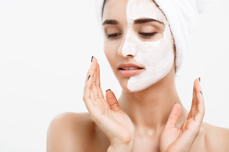 Beauty Skin Care Concept - Beautiful Caucasian Woman Face Portrait applying cream mask on her facial...