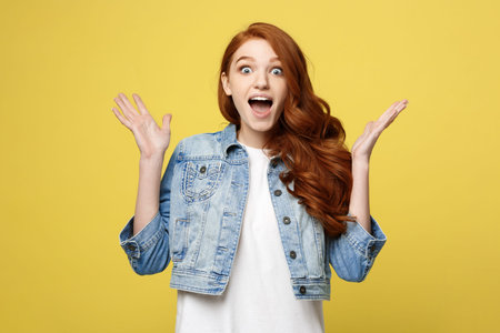 Surprised red hair teenage girl show shocking expression with something. Isolated on Bright Yellow Background. Copy space.の写真素材