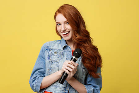 Lifestyle and People Concept: Expressive girl singing with a microphone, isolated bright yellow background.の写真素材