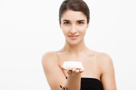 Beauty Youth Skin Care Concept - Beautiful Caucasian Woman Face Portrait smiling and holding cream jar for body and skin.Isolated over white background.の写真素材