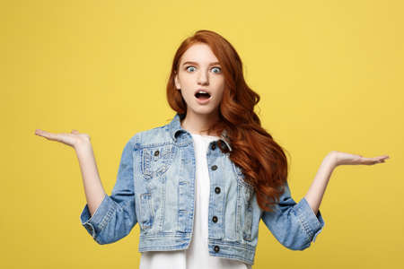 Lifestyle Concept: Surprised young woman with hand on side over golden yellow background. Looking at camera.の写真素材