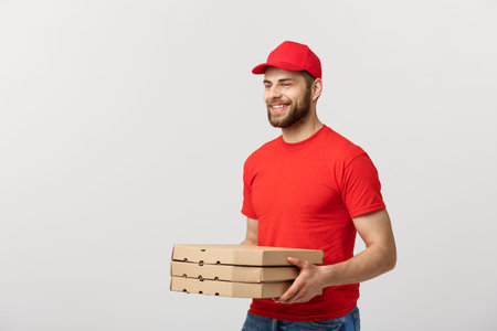 Delivery Concept: Young caucasian Handsome Pizza delivery man holding pizza boxes isolated over grey...