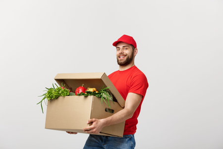 Delivery Concept - Handsome Cacasian delivery man carrying package box of grocery food and drink...