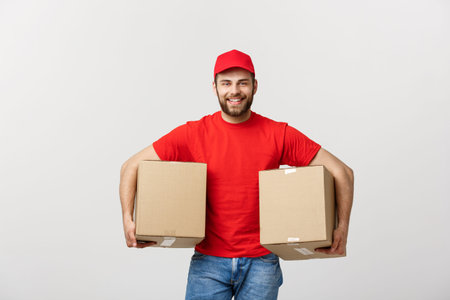 Delivery Concept: Smiling handsome caucasian delivery man holding a paper box. Isolated over grey...