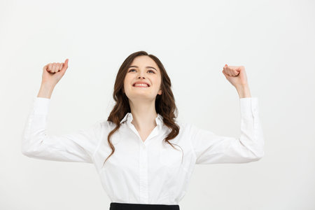 Business Concept: young happy businesswoman with hands in the air is celebrating success on white...