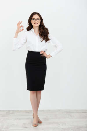 Portrait of Business woman holding ok finger sign isolated on plain white background in studio.の写真素材