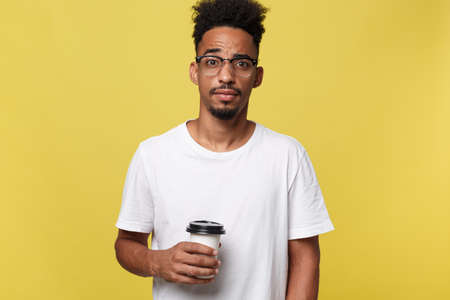 Stylish young afro american man holding cup of take away coffee isolated over yellow backgroundの写真素材