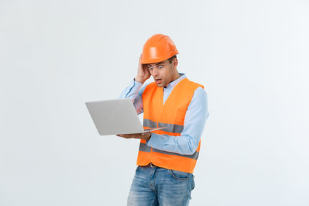 Portrait of a surprised engineer holding his laptop over gray background.