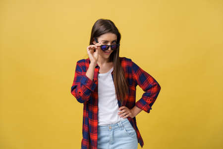 Portrait of a beautiful girl in round glasses on a yellow background in the studio.の写真素材