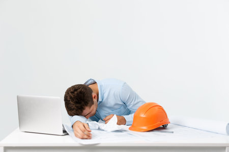 young attractive engineer man feeling tired at work place