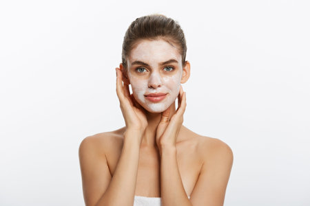 Close up of a woman with cosmetic facial mask applied over her face looking away.