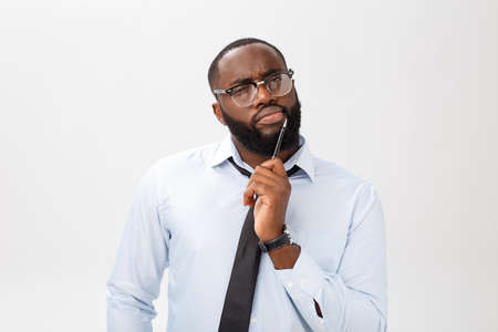 Portrait of a pensive African American businessman in a gray suit thinking with pen on his hand.の写真素材
