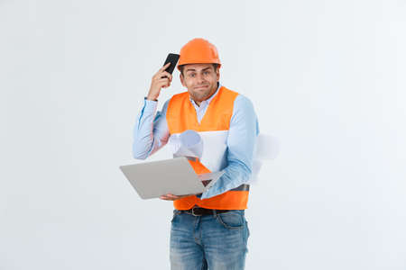 Disappointed handsome engineer wearing orange vest and jeans with helmet, isolated on white backgroundの写真素材