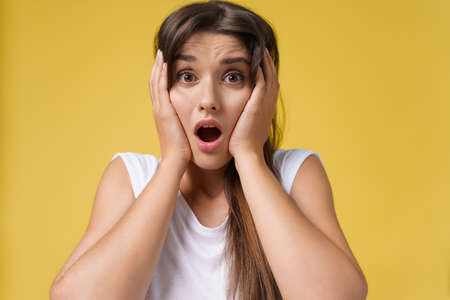 Close up Portrait young beautiful attractive student girl shocking with something. Bright Yellow Background. Copy spaceの写真素材