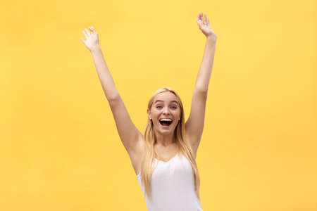 Young beautiful happy girl with hand in the air portrait isolated on yellow background.の写真素材
