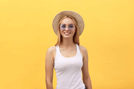Happy stylish modern woman with modern shaped sunglasses laughing looking at you camera isolated on yellow background. Happiness conceptの写真素材