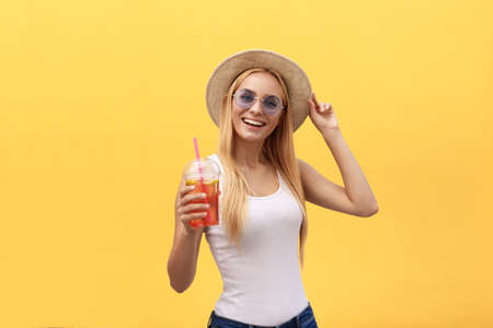 Happy stylish modern woman with modern shaped sunglasses laughing looking at you camera isolated on yellow background. Happiness conceptの写真素材