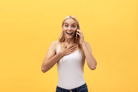 Surprised young woman wearing white clothes while looking at camera isolated on yellow background.