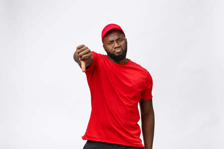 Delivery Concept - Portrait of Serious African American delivery man showing silly aggressive expression and unhappy. Isolated on Grey studio Background. Copy Space.の写真素材