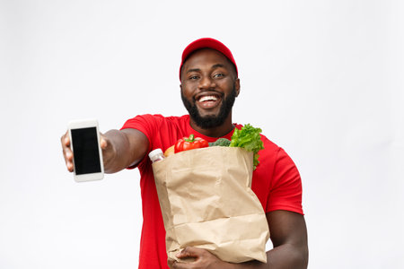 Delivery Concept - Portrait of Handsome African American delivery man or courier showing mobile...