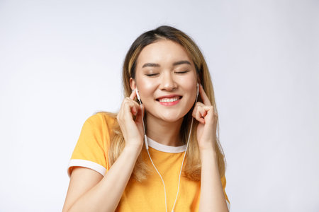 Portrait of happy Asian young woman listen to music with headphone.