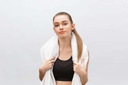 Healthy beautiful sportswoman wearing tracksuit with towel looking isolated over gray backgroundの写真素材
