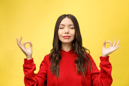 People, yoga and healthy lifestyle. Gorgeous young woman dressed in light red sweater keeping eyes...