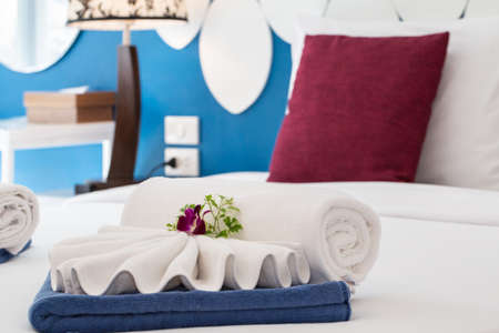 Beautiful freshly made bed in the tropics with fresh orchid.の写真素材