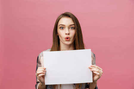 Young caucasian woman holding blank paper sheet over isolated background scared in shock with a surprise face, afraid and excited with fear expressionの写真素材