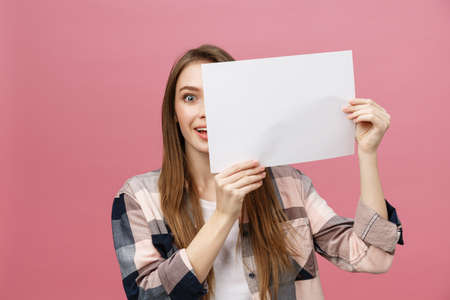 Young caucasian woman holding blank paper sheet over isolated background scared in shock with a surprise face, afraid and excited with fear expressionの写真素材