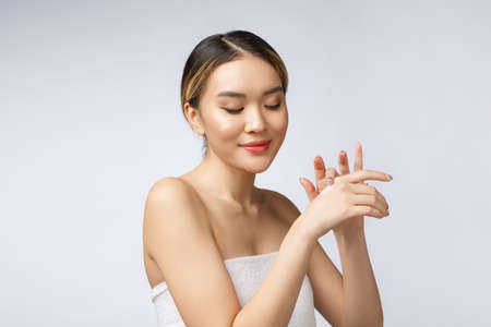 Asian woman applying cosmetic cream on skin on isolated white backgroundの写真素材