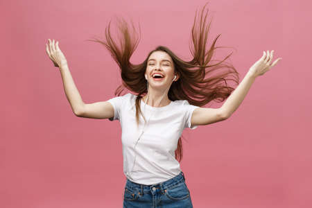 Lifestyle Concept. Young woman using phone for listening to music on pink backgroundの写真素材