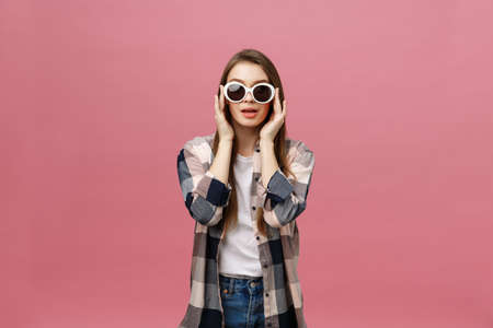 Photo closeup of charming womanwith long hairstyle wearing trendy sunglasses looking at camera with fashion look isolated over pink backgroundの写真素材