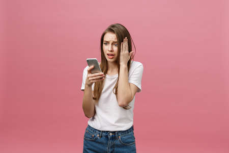 Serious young woman talking on phone isolated on pink. Copy space and fashion. Mock up.の写真素材