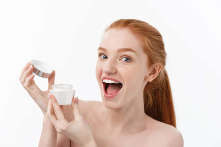 portrait of beautiful woman smiling while taking some facial cream isolated on white background with copy space.の写真素材