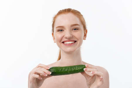 Cheerful happy beautiful girl with cucumber on her hand - isolated on whiteの写真素材
