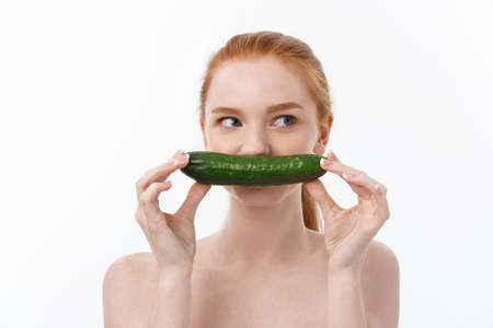 Cheerful happy beautiful girl with cucumber on her hand - isolated on whiteの写真素材