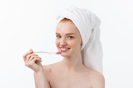 Portrait of young woman with toothbrush on grey background.