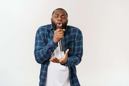Portrait of cheerful positive chic handsome african man holding microphone singing song. Isolated on white background.の写真素材