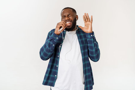 Handsome Afro American man in casual clothes is listening to music using a smart phone and smiling.の写真素材
