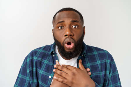surprised young dark-skinned African American man student staring at camera with shocked look.の写真素材