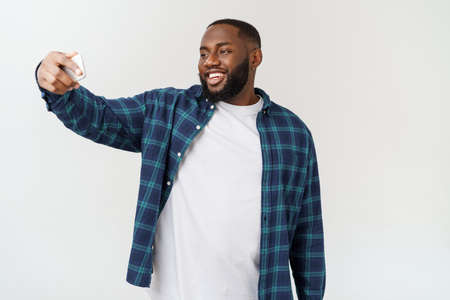 young afro american black man smiling happy taking selfie self portrait picture with mobile phone.の写真素材