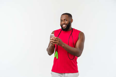 Mature fit African American man texting on mobile and holding elastic rope.の写真素材