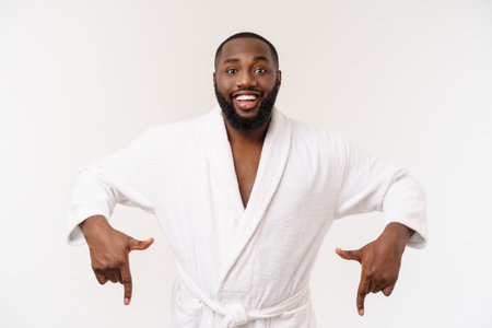 Black guy wearing a bathrobe pointing finger with surprise and happy emotion. Isolated over whtie background.の写真素材
